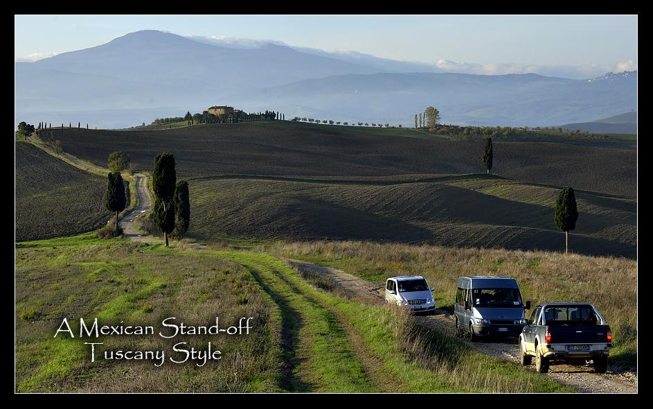 The two vans were forced to back up to the stand of Cypress trees to allow the pick-up truck to pass. What is not obvious here is that the single lane dirt road is between two deep ditches on either side making a simple veer into the grass impossible.
